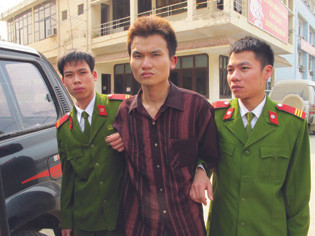 Đối tượng Đỗ Văn Nhuận (giữa) bị dẫn giải ra xe cảnh sát