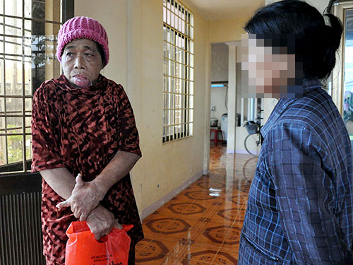 Những vết thâm tím còn hằn trên khuôn mặt của bà Chín (trái) do bị con đánh đập