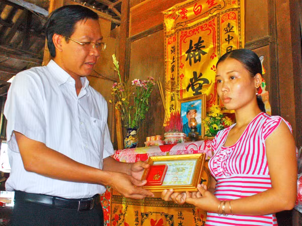 Anh Phan Văn Mãi trao huy hiệu “Tuổi trẻ dũng cảm” (của T.Ư Đoàn truy tặng đoàn viên Huỳnh Văn Tùng) cho vợ anh Tùng