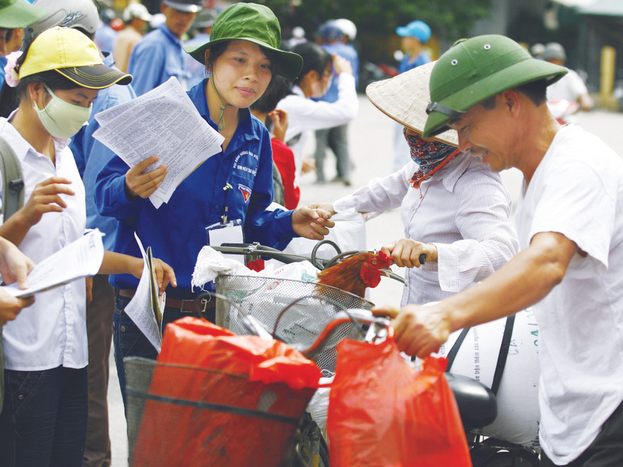 Sinh viên tình nguyện giúp đỡ vợ chồng chị Hoa (Nam Định) đưa con lên Hà Nội thi. Ảnh: Hồng Vĩnh