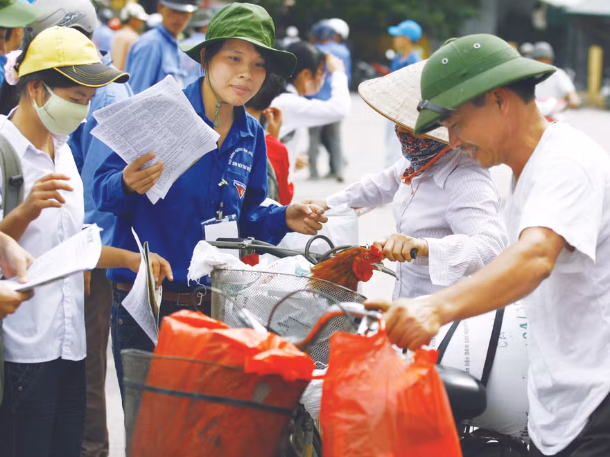 Sinh viên tình nguyện giúp đỡ vợ chồng chị Hoa (Nam Định) đưa con lên Hà Nội thi. Ảnh: Hồng Vĩnh