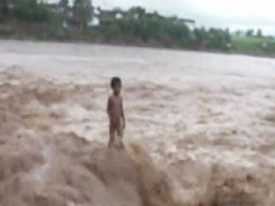 Cậu bé bốn tuổi đứng giữa dòng nước lũ