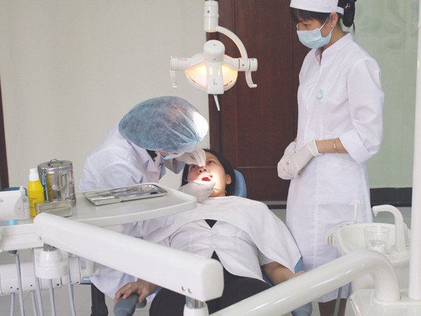 Bác sĩ khám răng cho bệnh nhân. Ảnh T.Hà