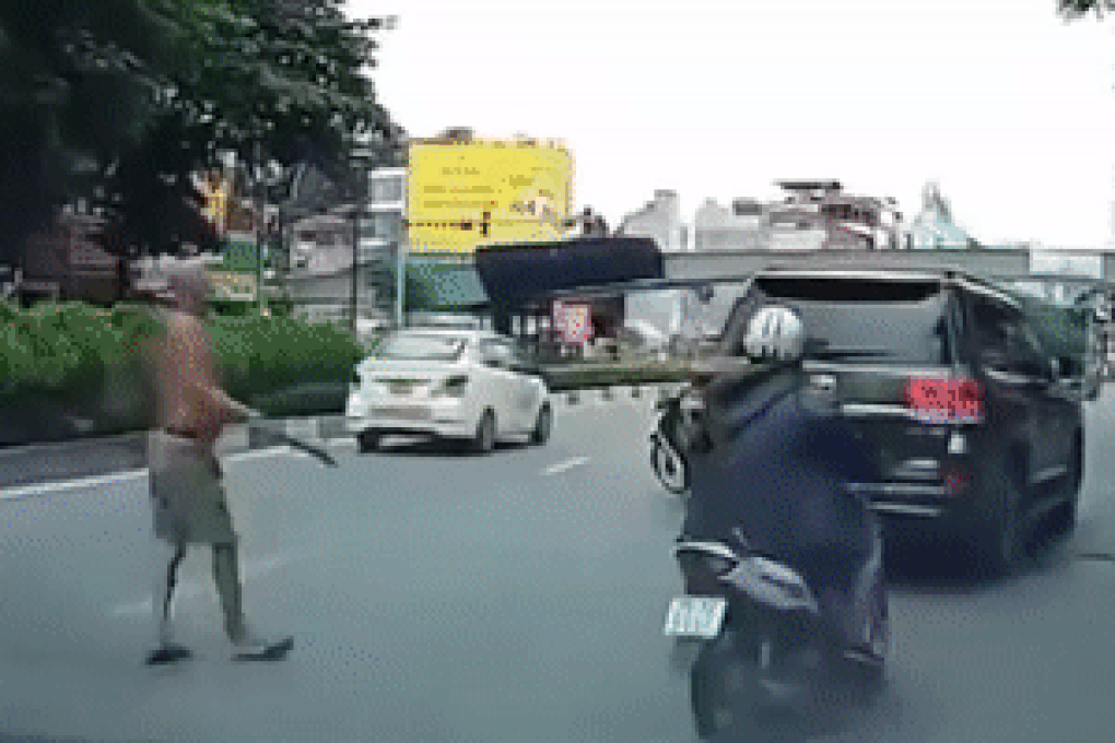 Người đàn ông phi dao trúng kính sau của chiếc ôtô.