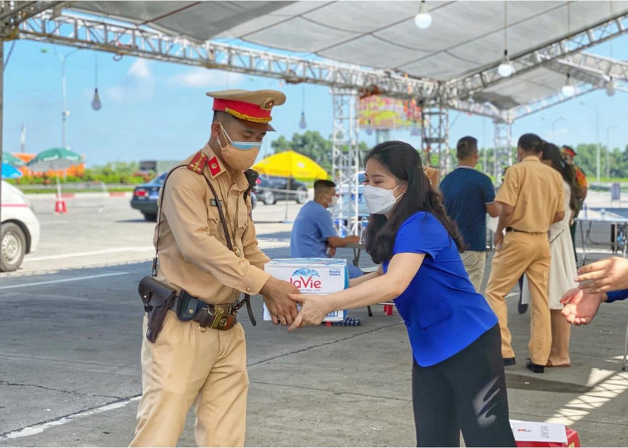 Chị Chu Hồng Minh, Bí thư Thành Đoàn Hà Nội trao tặng nước uống cho lực lượng trực tại các đểm chốt kiểm soát của Thủ đô