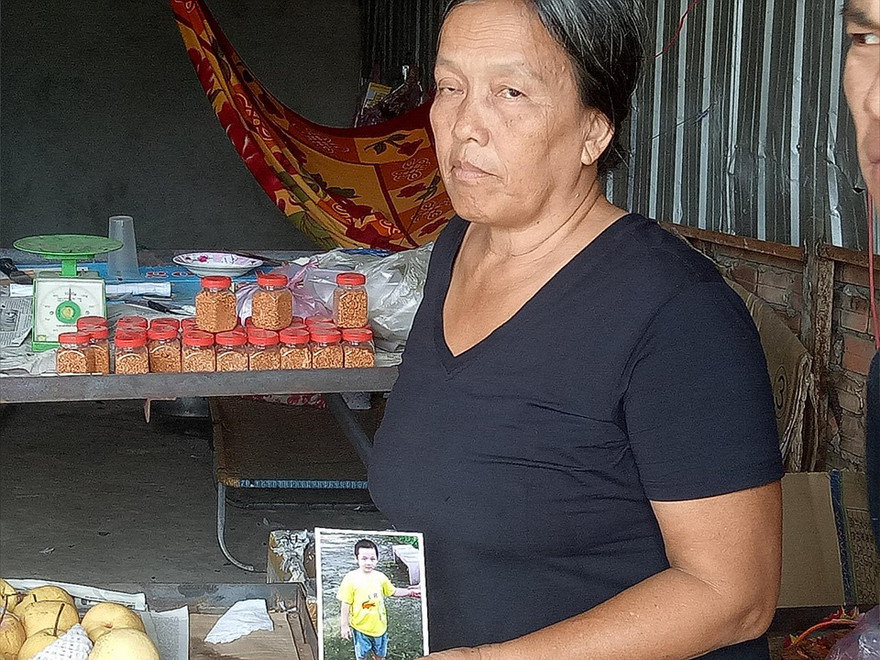 Bà ngoại của cháu L. cầm tấm hình của cháu mình đi tìm kiếm nhiều nơi