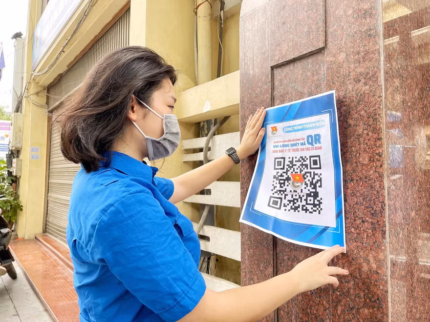 Chị Nguyễn Mai Anh, Phó Bí thư Đoàn cơ quan, Bí thư Chi đoàn Văn phòng Thành Đoàn Hà Nội dán mã QRcode tại cổng Thành Đoàn Hà Nội.