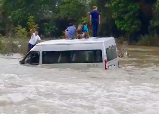 Chiếc xe ô tô chở nhiều khách bị nước cuốn trôi trong sự kinh hãi của mọi người. Ảnh: PV