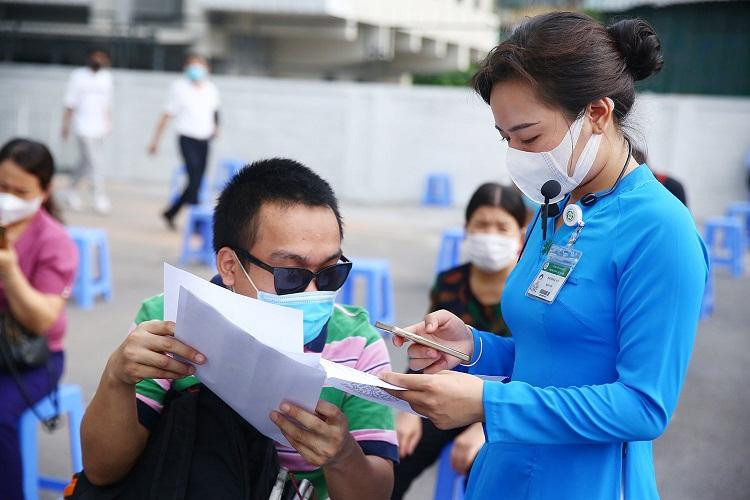 Người đến tiêm được hướng dẫn viên (áo dài xanh) hỗ trợ khai báo y tế và hoàn thiện thủ tục giấy tờ. Ảnh: Bệnh viện cung cấp