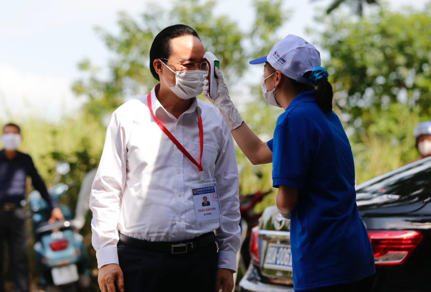 Bộ trưởng được lực lượng Y tế, tình nguyện viên đo nhiệt độ tại điểm thi.