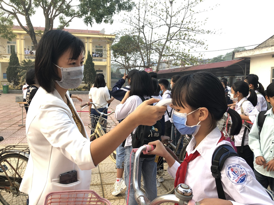 Giáo viên đo nhiệt độ cho học sinh trong ngày tới trường tại Vĩnh Phúc.