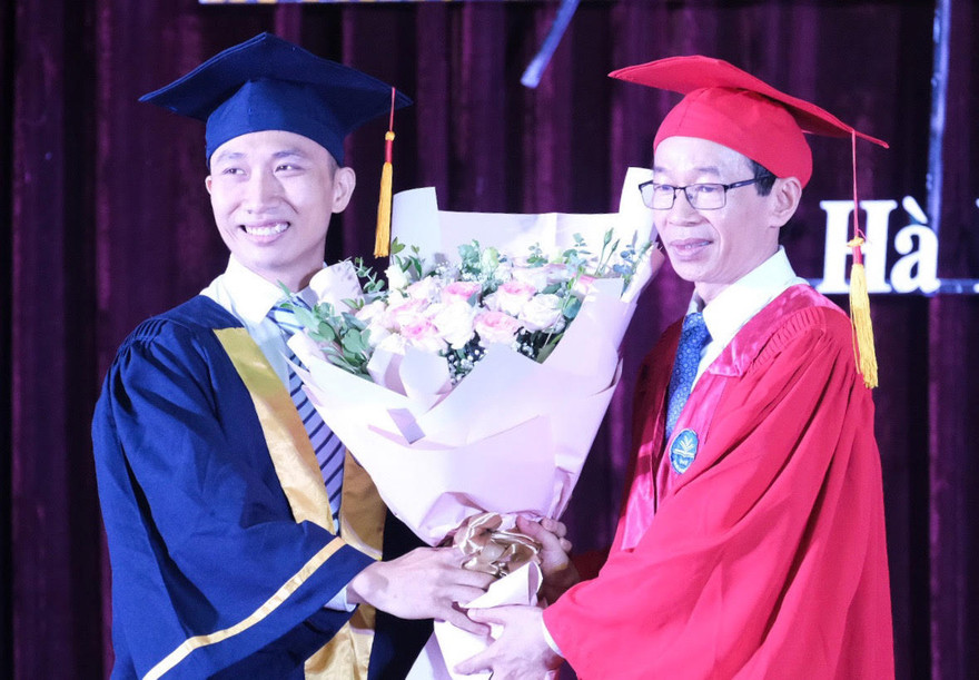 Phạm Việt Dũng (bên trái) nhận hoa chúc mừng của GS.TS Nguyễn Văn Minh, hiệu trưởng trường ĐH Sư phạm Hà Nội trong lễ tốt nghiệp