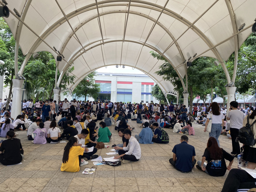 Phụ huynh, thí sinh ngồi la liệt ở sân trường để lấy số. Ảnh HC