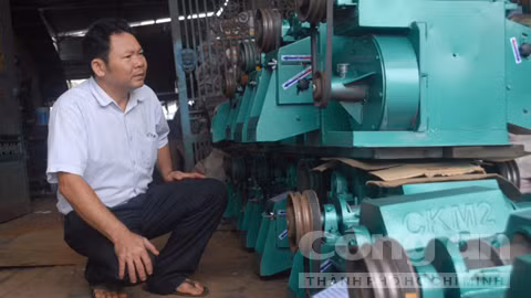 Nông dân Đặng Văn Bẩy bên Cơ sở Cơ khí Toàn Thắng do anh thành lập.