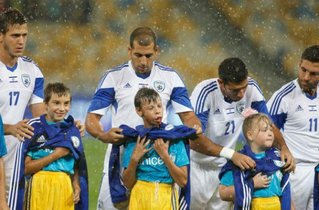 Các cầu thủ bóng đá Israel cởi áo khoác che mưa cho những cậu bé Ukraina trước một trận đấu bóng đá. Các cầu thủ bóng đá Israel cởi áo khoác che mưa cho những cậu bé Ukraina trước một trận đấu bóng đá.