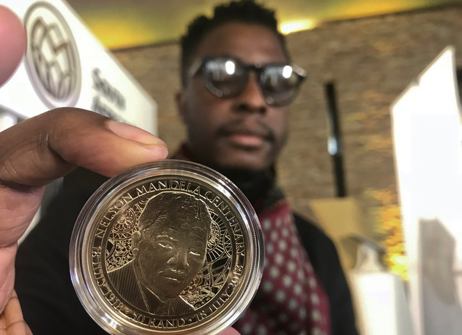Nghệ nhân Sindiso Nyoni cầm trên tay đồng xu vàng khắc họa hình ảnh cố Tổng thống Nelson Mandela. Ảnh: REUTERS.