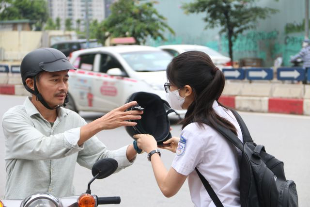 Phụ huynh khác vừa cởi bỏ mũ bảo hiểm, vừa căn dặn con Phụ huynh khác vừa cởi bỏ mũ bảo hiểm, vừa căn dặn con