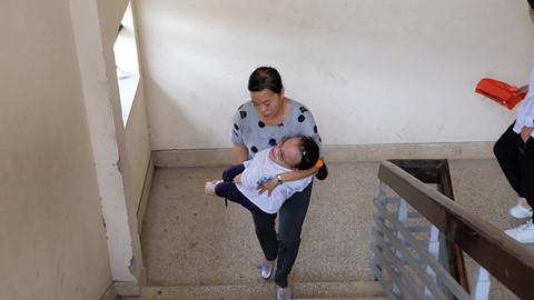 Hoài Thương được mẹ bế lên tầng 4 để làm vào phòng thi. ẢNH:LÃ NGHĨA HIẾU.