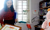 Tay phải cầm tấm bằng khen chống tiêu cực, tai trái chị "Nguyệt Hoài Đức" ôm hàng tệp những nội dung tin nhắn khủng bố, đe dọa trả thù. Phía sau tấm bằng khen chống tiêu cực