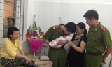 Con trai chị Phương trong vòng tay của hai cảnh sát đỡ đẻ giữa cơn giông