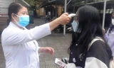 Đo thân nhiệt học sinh trước khi vào lớp tại Trường THPT Nguyễn Trường Tộ, Huế, vào sáng 13/12