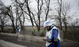 Thành viên phái bộ OSCE điều tra mảnh đạn pháo gần làng Shirokino, Ukraine. (Nguồn: AFP/TTXVN)
