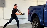 Một phóng viên nước ngoài đang dùng búa tạ thử sức chịu đựng của Ford F-150.