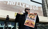 Một khán giả cầm poster phim The Interview trước rạp phim ở Los Angeles, California vào ngày công chiếu 25/12. Ảnh: Reuters.