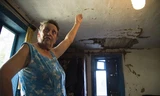 Bà Ina Tipunova chỉ cho phóng viên thấy lỗ hổng trên trần nhà bếp khi thi thể nạn nhân MH17 rơi xuống từ máy bay định mệnh. Ảnh: Daily Mail.
