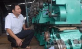 Nông dân Đặng Văn Bẩy bên Cơ sở Cơ khí Toàn Thắng do anh thành lập.