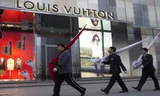 Các nhân viên Trung Quốc đi qua một cửa hiệu Louis Vuitton ở Bắc Kinh. Ảnh: AP.