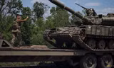 Một lính Ukraine hướng dẫn xe tăng lên xe tải ở vùng Donest ngày 8/6. (Ảnh: Reuters)