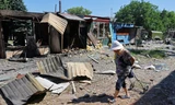 Một cụ bà đi qua khu chợ đổ nát ở Donetsk ngày 19/6. (Ảnh: Reuters)