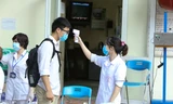 Tình nguyện viên đo thân nhiệt cho thí sinh tại kì thi tốt nghiệp THPT 2020