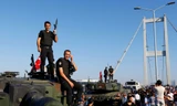 Cảnh sát đứng trên nóc xe bọc thép sau khi binh lính tham gia đảo chính đầu hàng trên cầu Bosphorus ở Istanbul. Ảnh: Reuters.