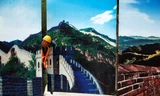 Một công nhân thò đầu khỏi hàng rào trang trí bằng tranh in đoạn Vạn Lý Trường Thành Bát Đạt Lĩnh, Bắc Kinh, hôm 1/9. Ảnh: Reuters.