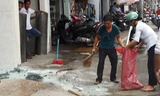 Người của tòa nhà thu dọn mảnh kính vỡ vụn dưới đường. Ảnh: An Nhơn