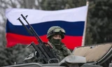 Một binh sĩ ở Crimea đứng trước lá cờ Nga. Ảnh: Reuters