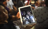 Thân nhân cầm trên tay bức ảnh được chụp trước khi các nam sinh mất tích. Ảnh: AFP