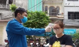 Thanh niên tình nguyện quận Đống Đa đo thân nhiệt người dân đến lấy mẫu xét nghiệm. ẢNH: NVCC 