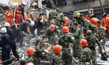 Các nhân viên cứu hộ dùng tay bới đống đổ nát cứu người mắc kẹt trong vụ sập nhà ở Ôn Châu, Trung Quốc.