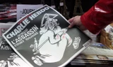 Một người Pháp cầm trên tay số báo đặc biệt của Charlie Hebdo phát hành ngày hôm nay kỉ niệm 1 năm vụ khủng bố tòa soạn. Ngoài trang bìa là dòng chữ "Một năm sau: Kẻ giết người vẫn còn đó".