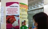  Người dân đọc khuyến cáo về phòng bệnh sởi. Ảnh: Thùy Giang/Vietnam+)