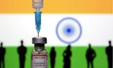 Một đồ chơi hình lọ vắc-xin và mũi tiêm được chụp trước quốc kỳ Ấn Độ. (Ảnh: Reuters)