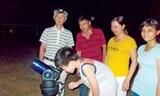 Thầy Fumitaka (ngoài cùng) hướng dẫn trẻ em và người dân Hội An quan sát bầu trời qua kính thiên văn. Ảnh: Nguyễn Trang