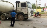 Thanh tra giao thông chống nạnh đứng trên bê tông rơi nhìn xe bồn vi phạm, trước mặt là biển báo cấm xe tải vào phố Kim Giang. Ảnh: A.T