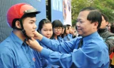 Anh Nguyễn Phi Long - Bí thư T.Ư Đoàn, Chủ tịch T.Ư Hội LHTN Việt Nam tặng mũ bảo hiểm cho ĐVTN tại lễ phát động. Ảnh: Xuân Tùng