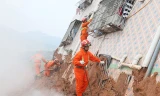 Tìm kiếm người mắc kẹt trong tòa nhà bị sập do lở đất. Ảnh: Xinhua