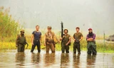 Đạo diễn (bìa phải) lội nước cùng dàn diễn viên.