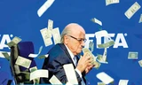 Chủ tịch FIFA Sepp Blatter lúng túng hứng cơn mưa tiền trong buổi họp báo. Ảnh: AP